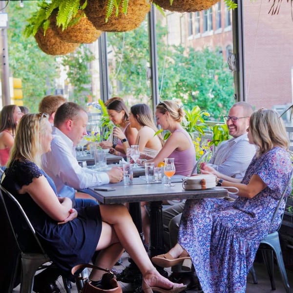 Patrons enjoying drinks and conversation at an outdoor dining area of Revolution House.
