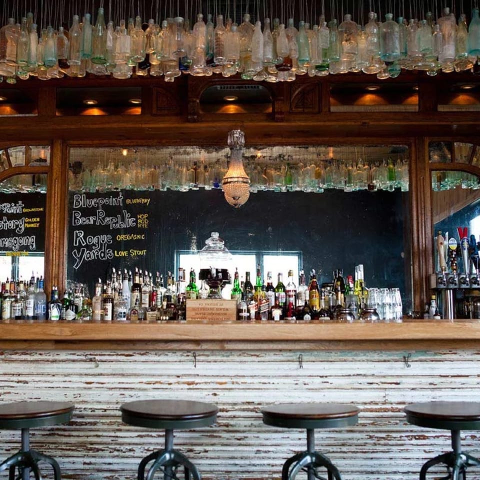 Revolution House bar with bottles hanging from the ceiling, liquor bottles, and bar stools.