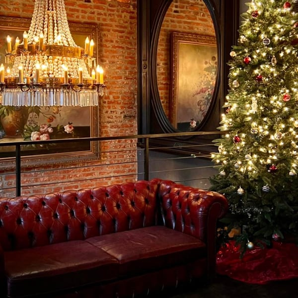 A festive Revolution House interior with a red leather couch, chandelier, and illuminated Christmas tree.