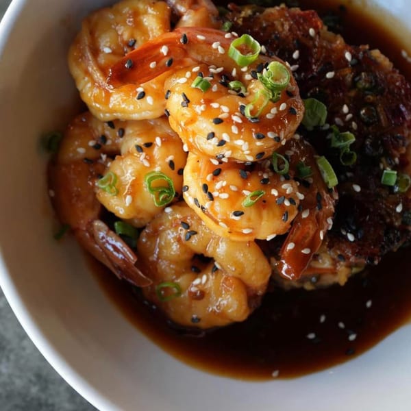 Revolution House's American cuisine features glazed shrimp with sesame seeds and scallions, served in a dark sauce.